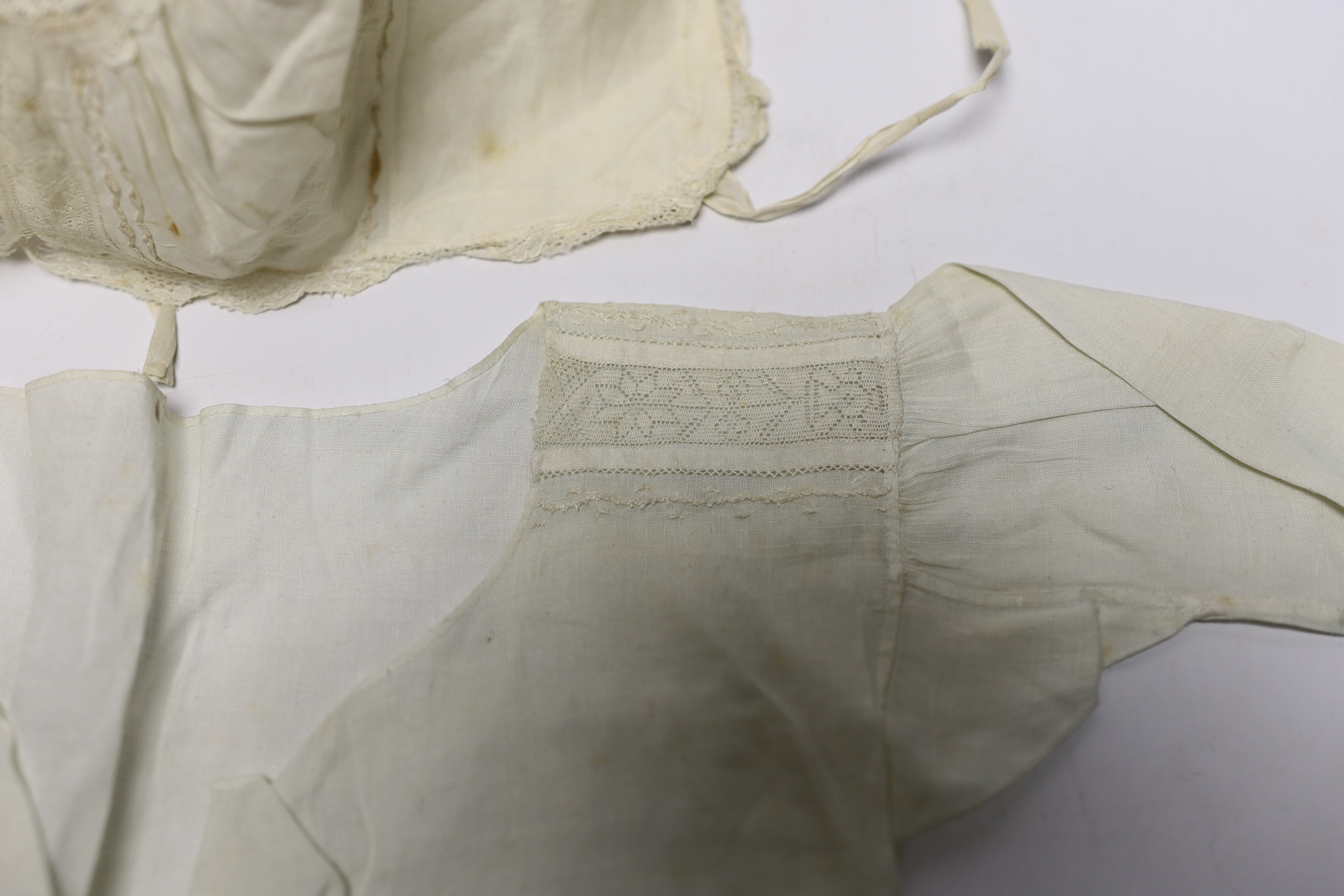 An early 18th century Hollie point insertion baby’s linen vest, three baby bonnets with Hollie point insertions and an early 18th century pair of Flemish bobbin lace lappets, a partly finished needlepoint length of lace,